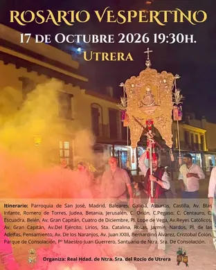 Personas portan un simpecado iluminado y envuelto en incienso durante un rosario vespertino en una calle de Utrera al anochecer