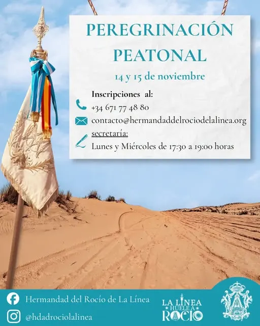 Simpecado con cintas de colores ondeando sobre dunas de arena bajo un cielo azul claro con información de peregrinación peatonal en cartel superpuesto