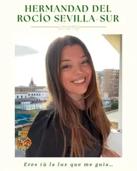 Mujer joven sonriente con cabello largo y suelto posa en un balcón urbano con edificios y cielo nublado al fondo