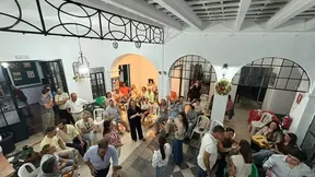 Grupo de personas de distintas edades compartiendo en un patio con sillas y guitarras en una convivencia festiva y animada en Badajoz