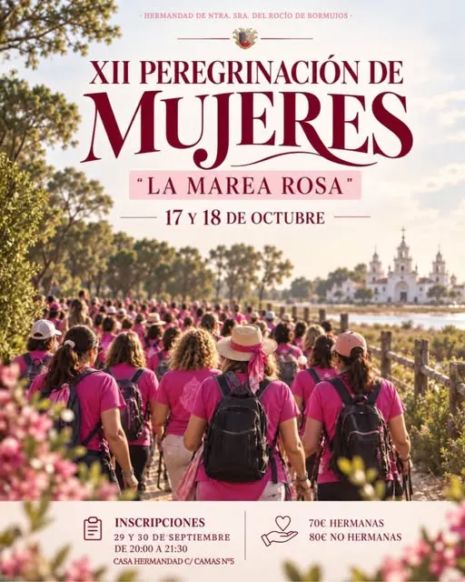 Grupo numeroso de mujeres vestidas con camisetas y pañuelos rosas caminando hacia la aldea del Rocío con la ermita visible al fondo bajo un cielo despejado
