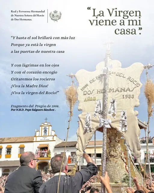 Estandarte blanco de la Hermandad de Dos Hermanas con la imagen de la Virgen del Rocío y personas levantándolo frente a una plaza llena de gente bajo un cielo azul con nubes