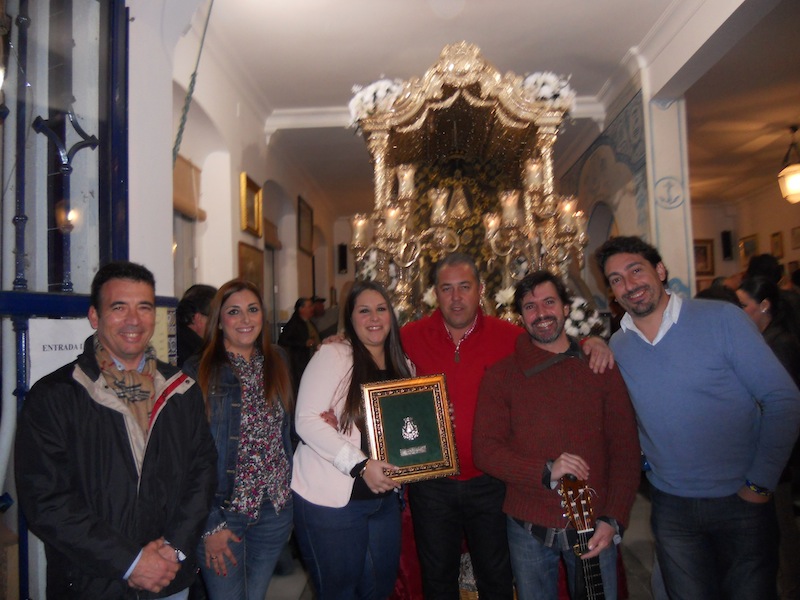 Foto de familia donde Beatríz, Alicia, Juana y Jose Monclova posan ante la Carreta que porta nuestro Simpecado con el Hermano Mayor, Juan Vázquez, y el Presidente de la Hermandad, Pedro Jesús Álvarez.