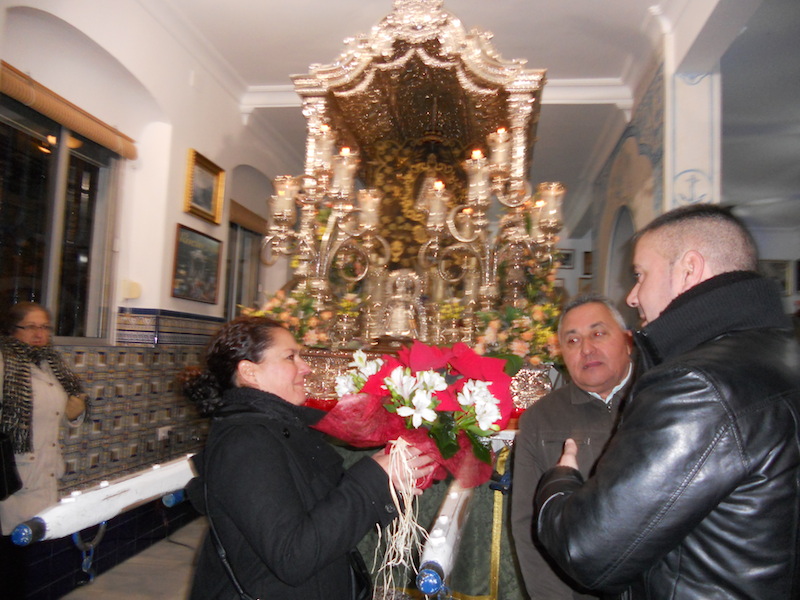 Antonio, más conocido por Cuqui, de la Peña El Soniquete, entrega a la camarista unas flores para ponerlas a los pies del Simpecado