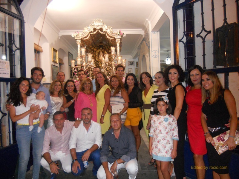Foto de familia en la que la mayoría de los miembros de la Casa Tintineo están con la Hermana Mayor ante la Carreta del Simpecado